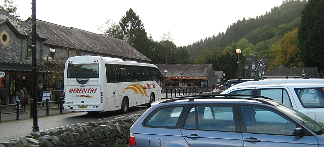 betwys-y-coed car park with a coach, cars, tourists and shops